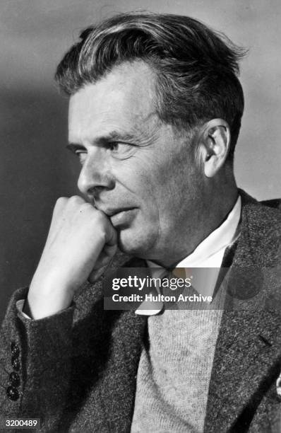 Portrait of British author Aldous Huxley holding a fist up to his face.