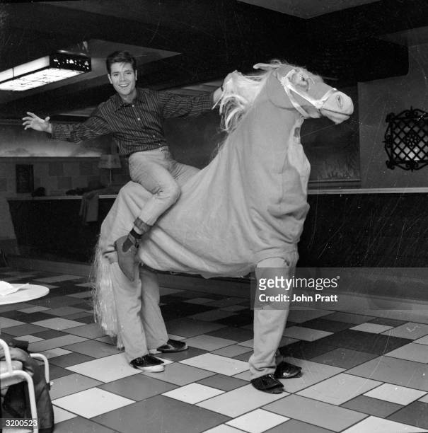 English pop star Cliff Richard riding a pantomime horse during rehearsals for the Christmas show 'Aladdin and his Wonderful Lamp' at the London...