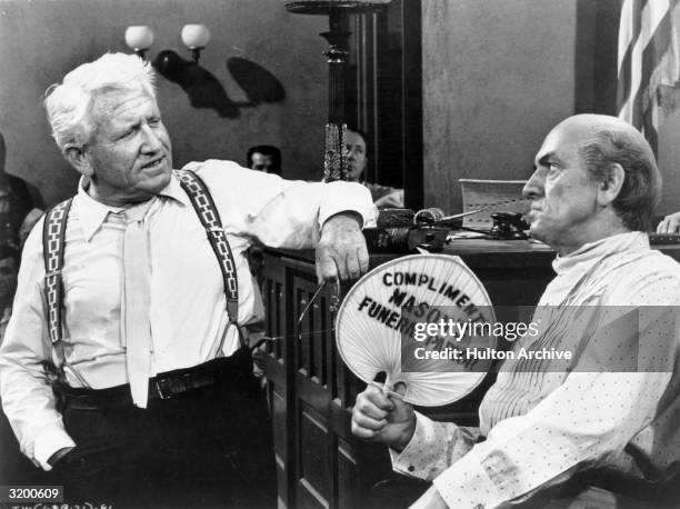 Actor Spencer Tracy cross-examines Fredric March in a courtroom as he fans himself in a still from the film, Inherit the Wind.