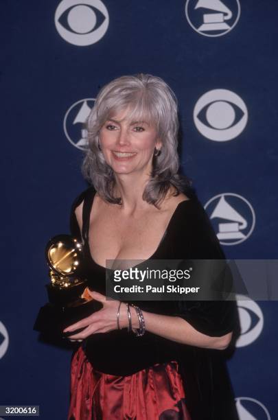 American singer, musician and songwriter Emmylou Harris holds her Grammy award for Best Country Collaboration with Vocals, which she shared with...