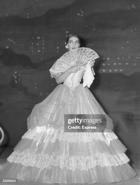 Greek-American opera singer Maria Callas , in costume, holds a fan while waiting in the wings before a performance of 'La Traviata' at the Royal...