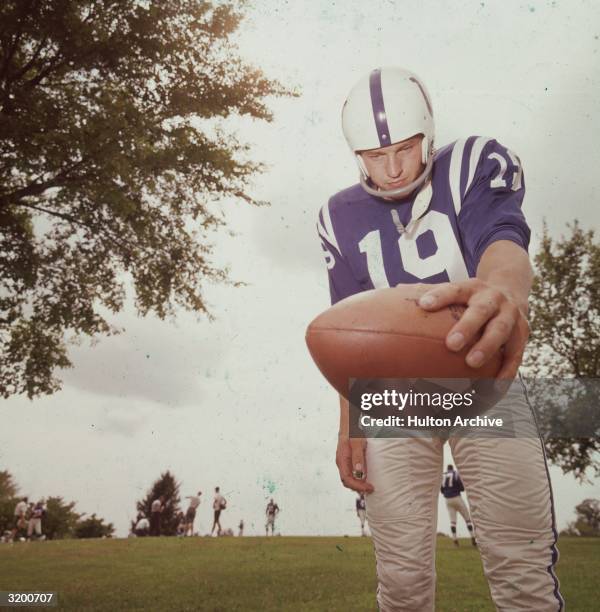 Low angle image of American football player John Unitas , quarterback for the Baltimore Colts, holding the ball in his left hand during practice on a...