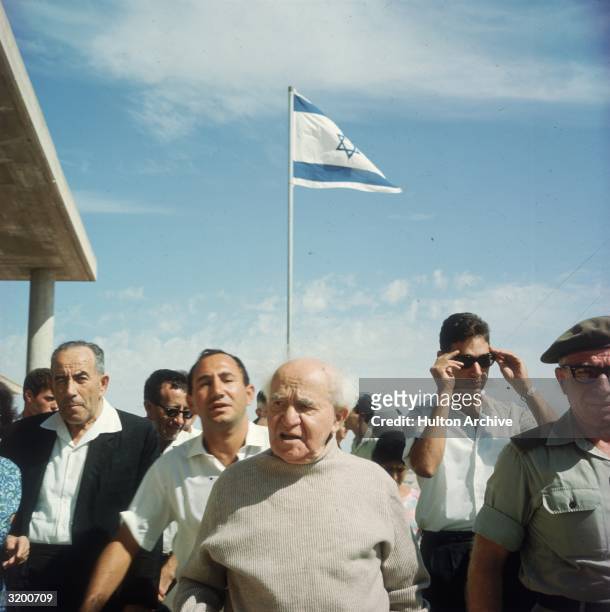 Israel's first prime minister, David Ben-Gurion , walks amid Israeli citizens and the Israeli flag, Israel.