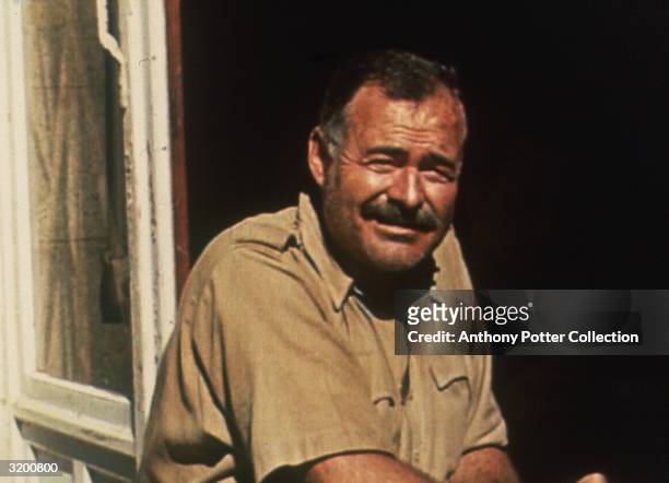 American author Ernest Hemingway squinting as he sits near an open window in the sun, Mont St. Michel, France. Hemingway was in France covering World...