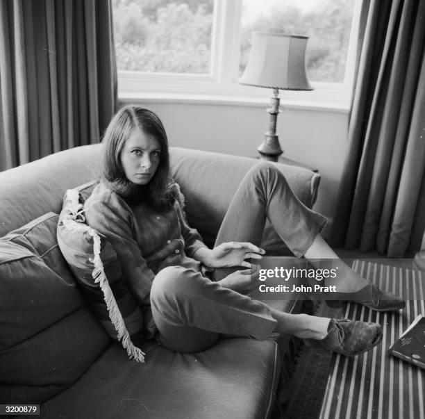 Casually dressed and sitting on a couch with her feet up on a table, twenty year old actress Sarah Miles on holiday at her father's home in Cornwall.