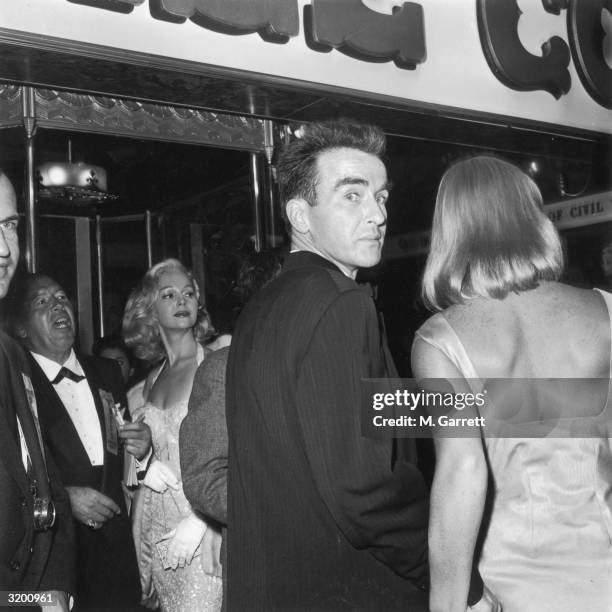 View from behind of American actor Montgomery Clift, looking over his shoulder, and Swedish actor May Britt, at the premiere of Canadian director...