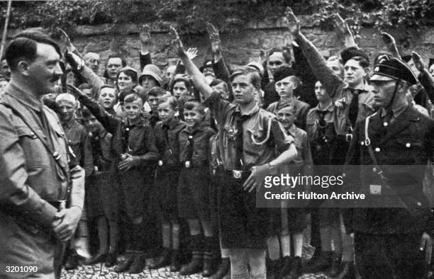 Nazi leader Adolf Hitler smiles while uniformed Saxon youths salute him outdoors in Erfurt, Germany.