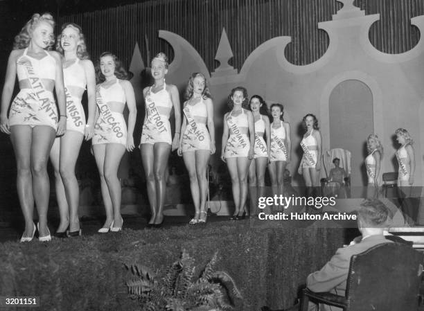 Eleven of the fifteen remaining finalists in the Miss America pageant parade across the stage in front of a panel of judges during the swimsuit...