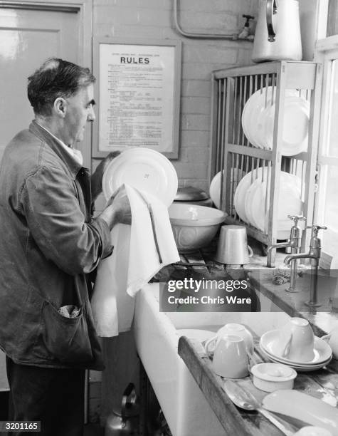 Resident does the washing up at a National Assistance Board Re-Establishment Centre for unemployed men at Henley-on-Arden in Warwickshire.