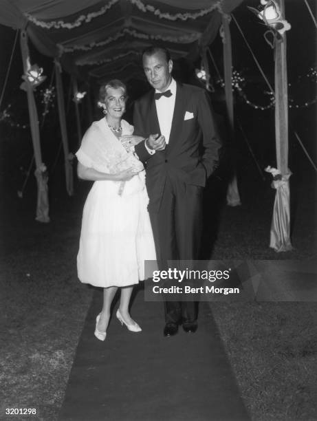 Full-length image of American actor Gary Cooper and his wife, actor Sandra Shaw , standing arm in arm on a red carpet at Marcia Meehan's debutante...