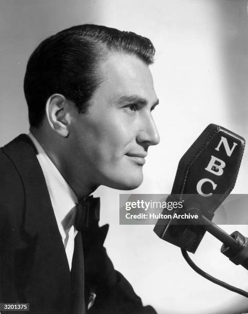 Headshot profile portrait of American jazz clarinettist and bandleader Artie Shaw, behind an NBC radio microphone.