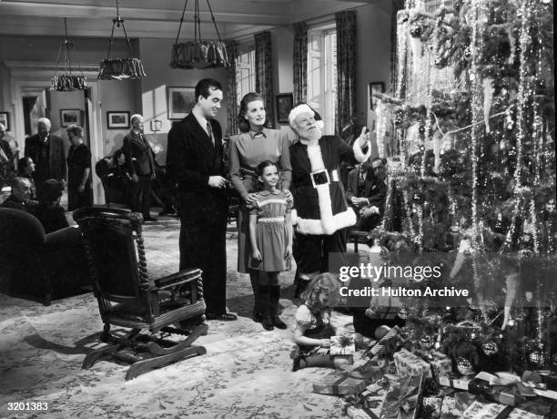 Actors John Payne, Maureen O'Hara, Edmund Gwenn , and young Natalie Wood stand before a Christmas tree in a still from director George Seaton's film,...