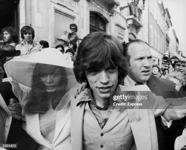 British rock singer Mick Jagger, of the Rolling Stones, and his new bride, Bianca Pérez-Mora Macías, make their way through crowds on their wedding...