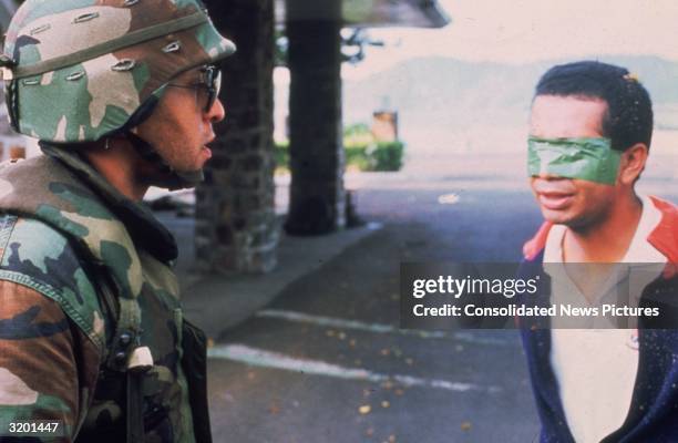 An American soldier stands in the street with a blindfolded Panamanian prisoner during the United States invasion, 'Operation Just Cause,' to oust...