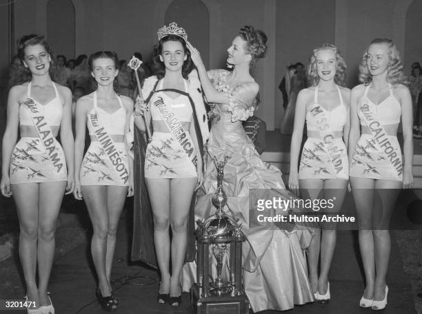 Miss America 1946 Marilyn Buferd crowns the new Miss America 1947, Barbara Jo Walker, of Memphis, Tennessee, as five other contestants smile,...