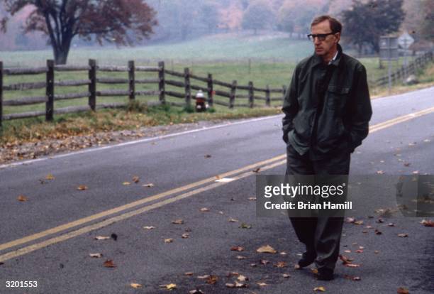 Full-length image of American film director, writer, and actor Woody Allen walking on a country road in a scene from his film, 'Mighty Aphrodite'.