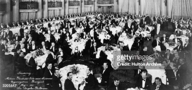 Interior view of formally dressed men and women seated at tables during the first organizational meeting of the Academy of Motion Picture Arts and...