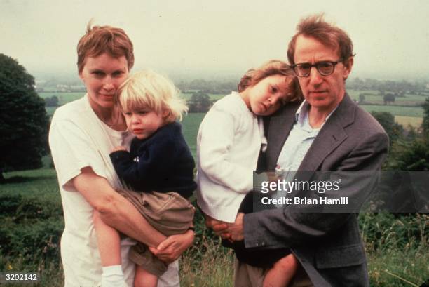 American actor Mia Farrow and her partner, American film director, writer, and actor Woody Allen, hold their children, Satchel and Dylan, on a hill...