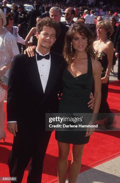 American actors Kirk Cameron and Chelsea Noble stand with their arms around each other on the red carpet at the Emmy Awards.