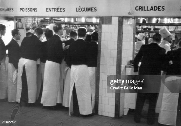 Waiters give their orders in the main restaurant kitchen at the Savoy Hotel, London. Original Publication: Picture Post - 488 - Savoy Hotel - unpub.