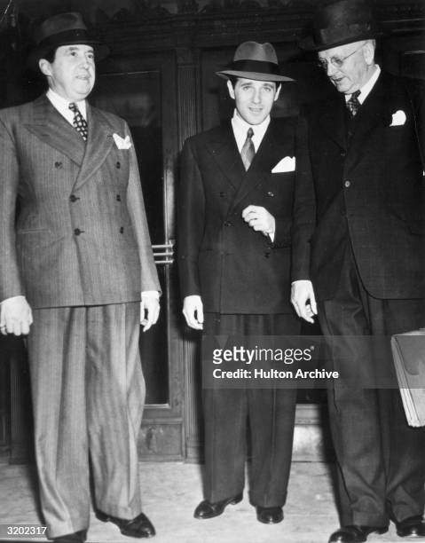 Full-length image of American gangster Benjamin 'Bugsy' Siegel standing with two unidentified men outside a building. Siegel established crime...
