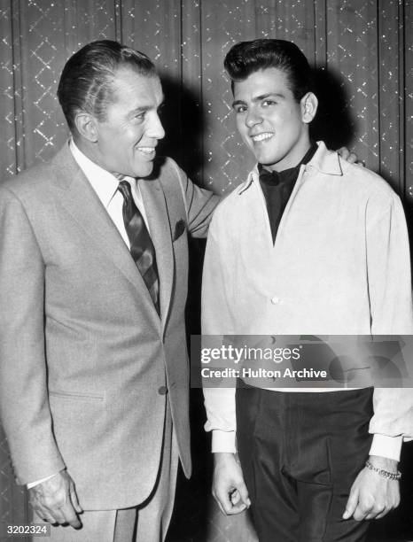 American variety show host Ed Sullivan poses with pop singer and actor Fabian in front of a stage curtain, possibly during a taping of 'The Ed...