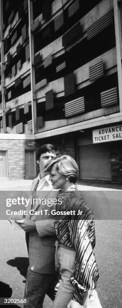 American baseball player Tom Seaver, wearing a pinstriped three-piece suit, looks backwards over his shoulder while walking with his wife, Nancy,...