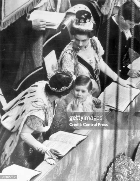 Queen Elizabeth the Queen Mother talking to her grandson, Prince Charles, during the coronation while Princess Margaret looks on.