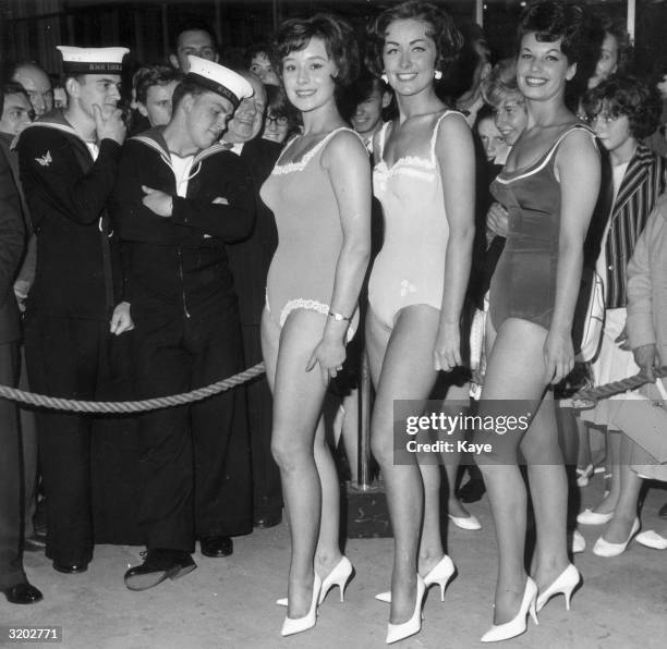 Two Royal Navy soldiers stare at the winners of the Miss Radio Show beauty pageant, Earls Court, London, England. L-R: Margaret Blake, winner Anne...