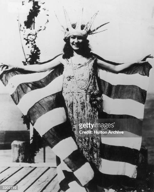 Full-length image of Margaret Gorman from Washington D.C. Smiling, wearing a large Statue of Liberty crown and a striped cape, as the first Miss...