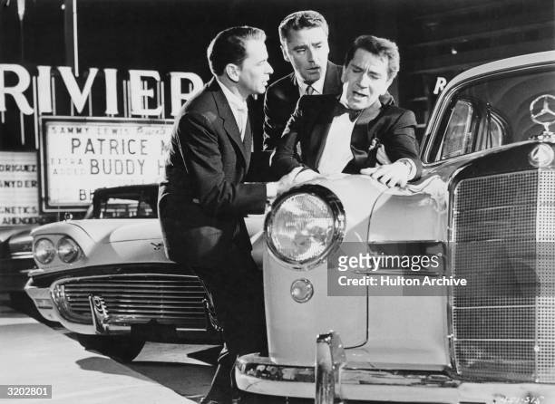 Actors Frank Sinatra and Peter Lawford support Richard Conte, while Conte leans against a Mercedes Benz, in a parking lot in Las Vegas, Nevada, in a...