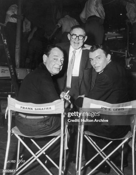 Comedian Joe E. Lewis and singer and actor Frank Sinatra look over their shoulders while sitting in each other's director's chair in front of Lewis'...