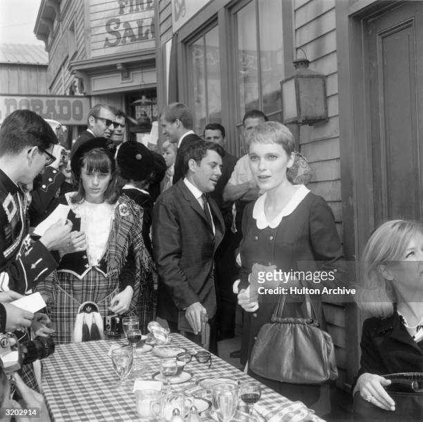 American actor Mia Farrow stands outdoors with a group of people attending a 20th Century Fox studio luncheon for Prince Philip, Los Angeles,...