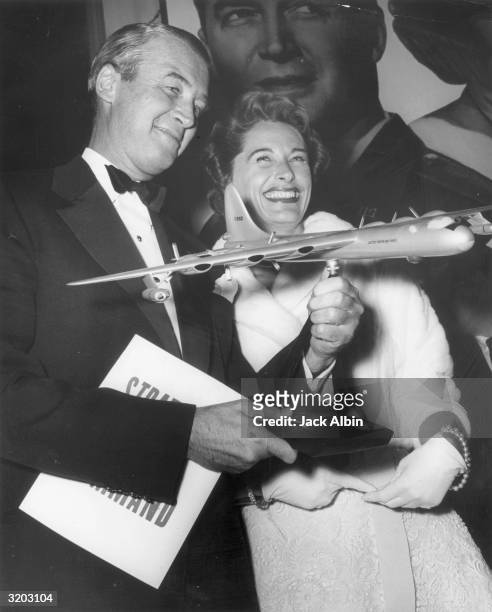American actor Jimmy Stewart , holding a scale model of a United States Air Force jet plane, with his wife, Gloria Stewart, at the premiere of...