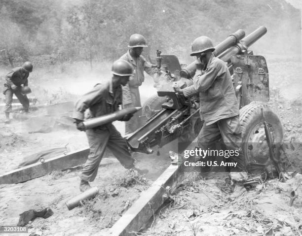 Three American soldiers of a U.S. Artillery gun crew loading a howitzer during the Korean war.