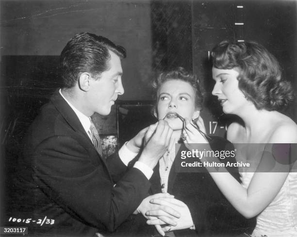 American actors Dean Martin and Polly Bergen apply actor Marion Marshall's lipstick on the set of director Hal Walker's film, 'That's My Boy'.