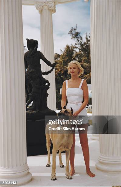 American socialite C.Z. Guest with a large Great Dane dog, at her Grecian temple pool on the ocean-front estate, Villa Artemis, Palm Beach, Florida,...