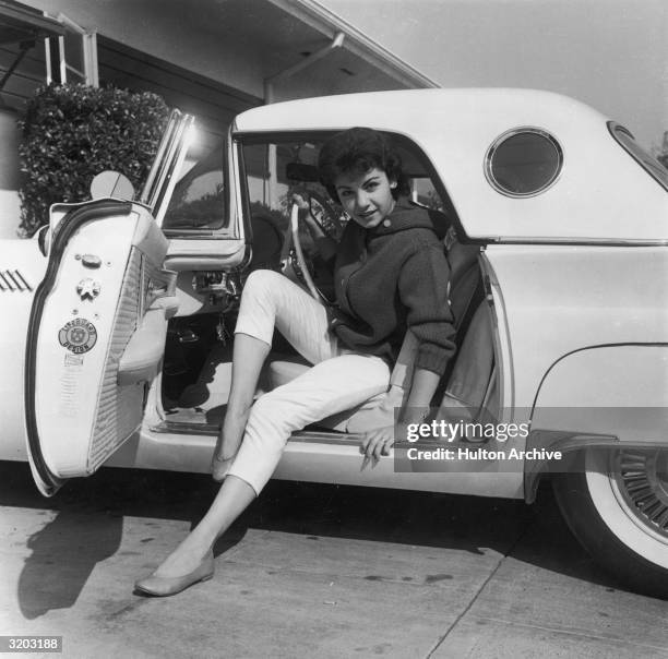 Portrait of American singer and actor Annette Funicello posing with her legs stretched out while preparing to exit a Ford Thunderbird.