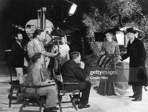 Full-length image of American film director Robert Z. Leonard discussing a scene with American actors Virginia Bruce and William Powell on the set of...