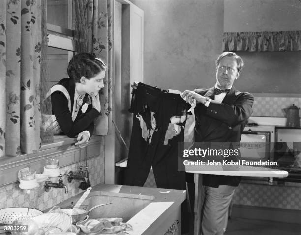 Director Robert Z Leonard holds up a tattered pair of trousers for Canadian actress Norma Shearer during the filming of their latest collaboration.