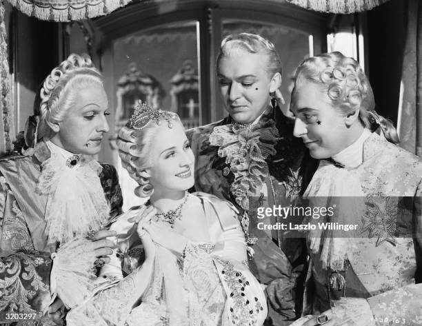 Norma Shearer , the eponymous star of the extravagant MGM production 'Marie Antoinette', surrounded by French courtiers.