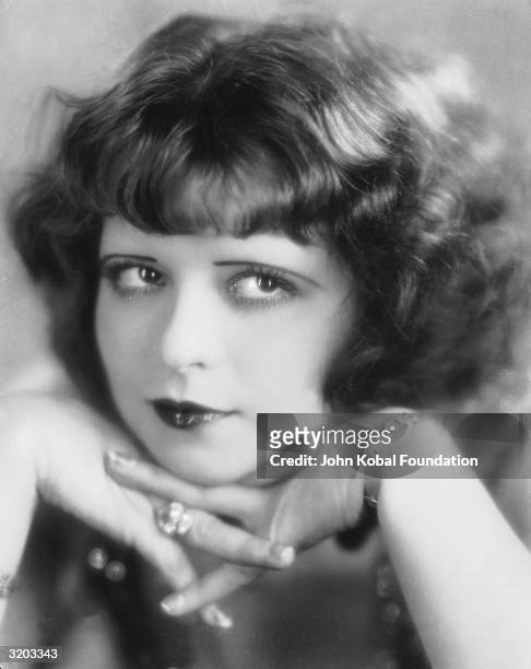 Hollywood film actress, Clara Bow rests her chin on her hands.