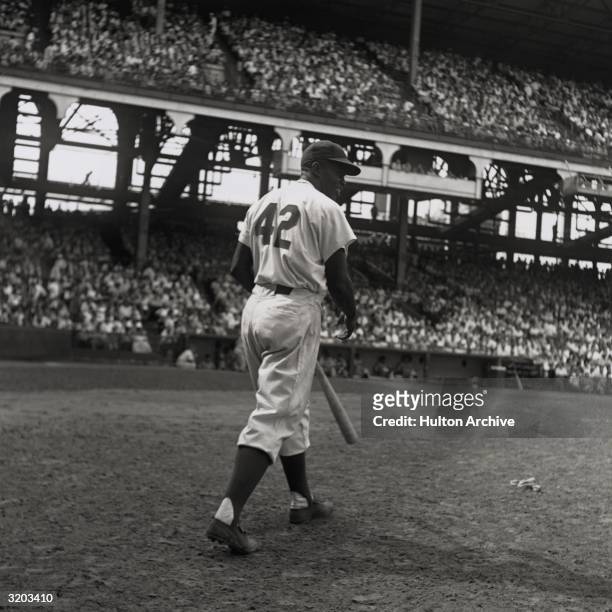 American baseball player Jackie Robinson, second baseman for the Brooklyn Dodgers, steps up to bat with his back to the camera during a game at a...