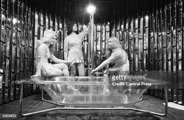 Models, Jackie Robinson, Barbara-Anna Milner and Maureen Tibble with a transparent Carron Constellation bathtub on display at the International...