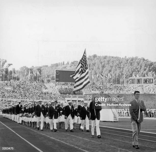 Full-length image of the American delegation, wearing suits and hats, marching inside Olympic Stadium during opening ceremonies for the Summer...