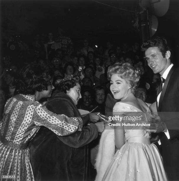 American actor Sandra Dee and her date, Mark Goddard, look over their shoulders during an autograph signing for crowds gathered at the premiere of...