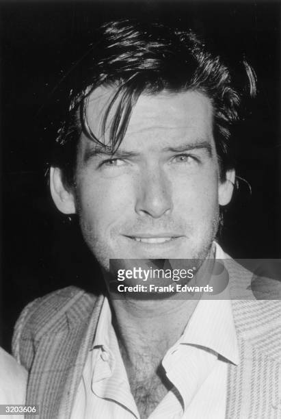 Headshot of Irish-born actor Pierce Brosnan wearing a tweed jacket with an open-collared shirt, knitting his brows while smiling at the Century Plaza...