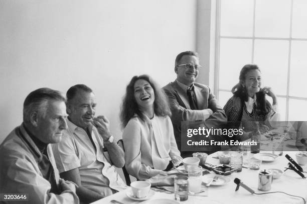 American film director Stanley Kramer sits at a banquet table with actors John Mills, Faye Dunaway, George C. Scott and Trish Van Devere while they...