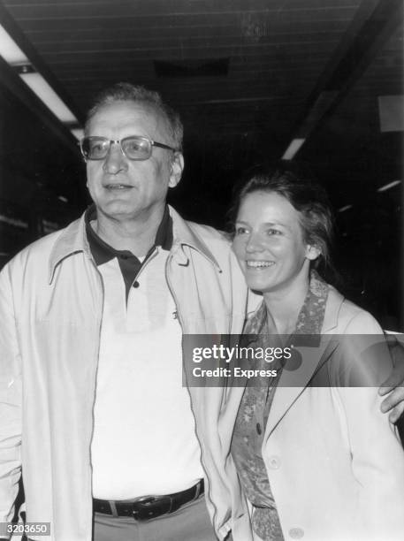 American actor George C Scott holds his around his wife, Trish Van Devere, at Heathrow Airport, London, England. The couple were in England to costar...