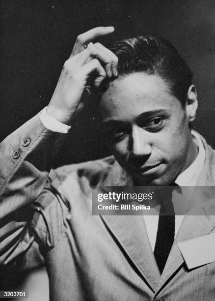 Headshot of jazz musician Horace Silver, wearing a jacket and tie, scratching his head.